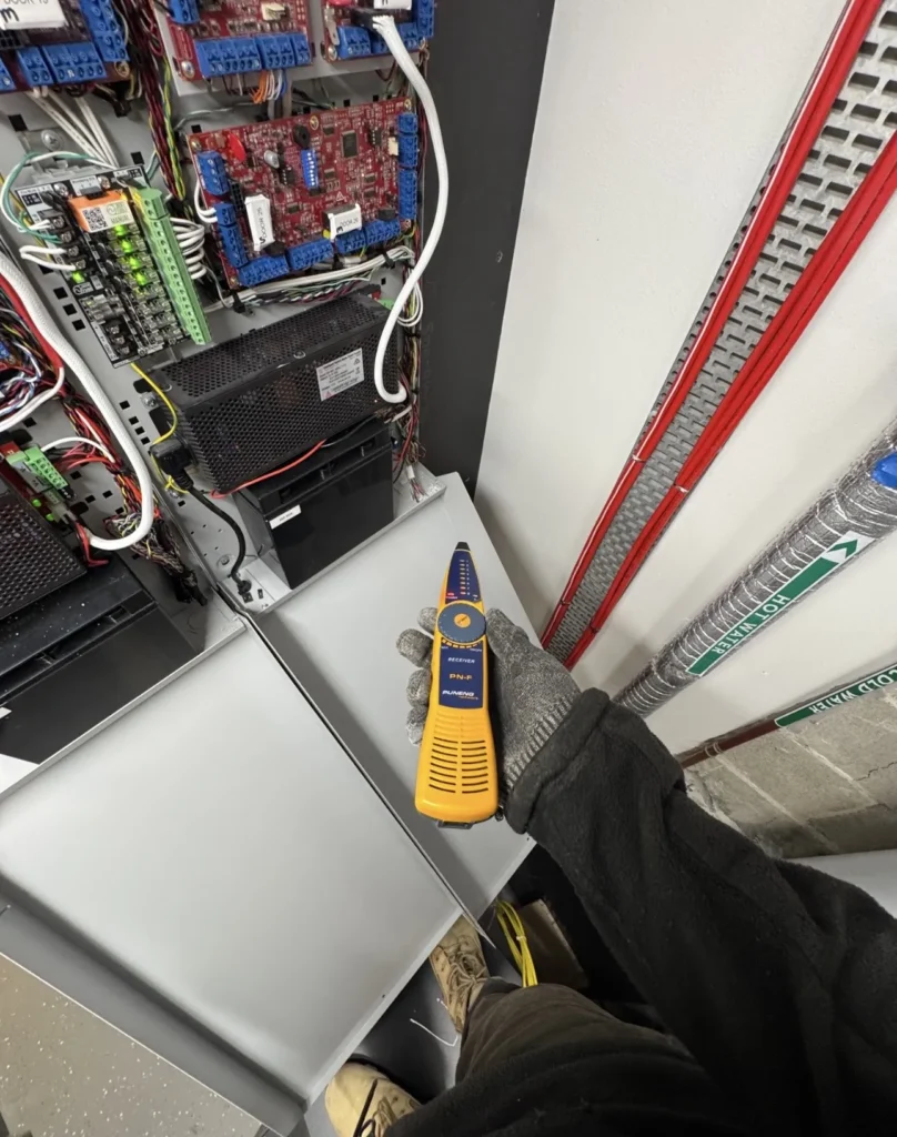 Technician testing cabling at a security equipment panel
