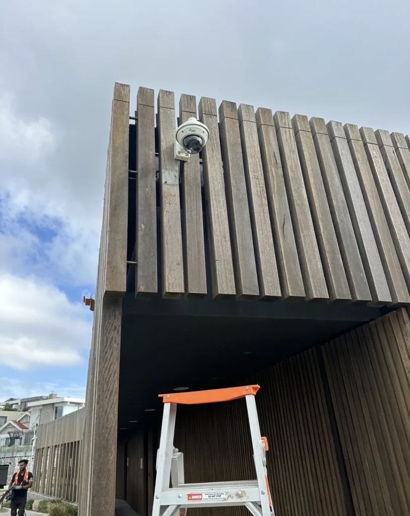 Security camera mounted high on an external timber-batten facade