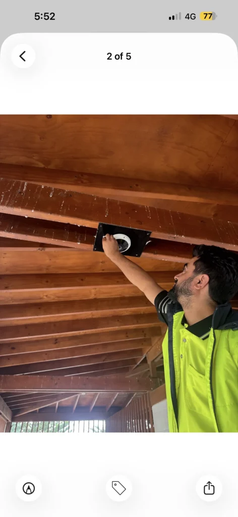 Technician installing a CCTV dome camera on a timber pergola ceiling